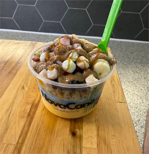 An açaí bowl piled with banana, berries and a caramel drizzle.