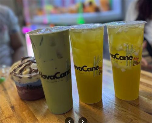 Three NovaCane cups of blended juice on a wood table.